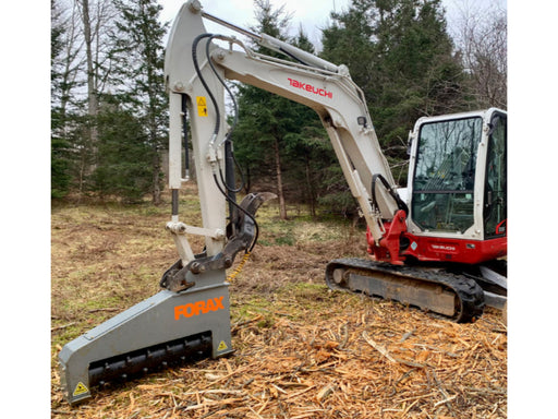 Forax XD36 mulcher mounted on compact excavator clearing brush and vegetation in a forested area.