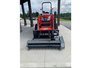 Small red tractor with a attachments on a concrete surface