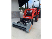 Red compact tractor with a front attachment on a concrete surface.